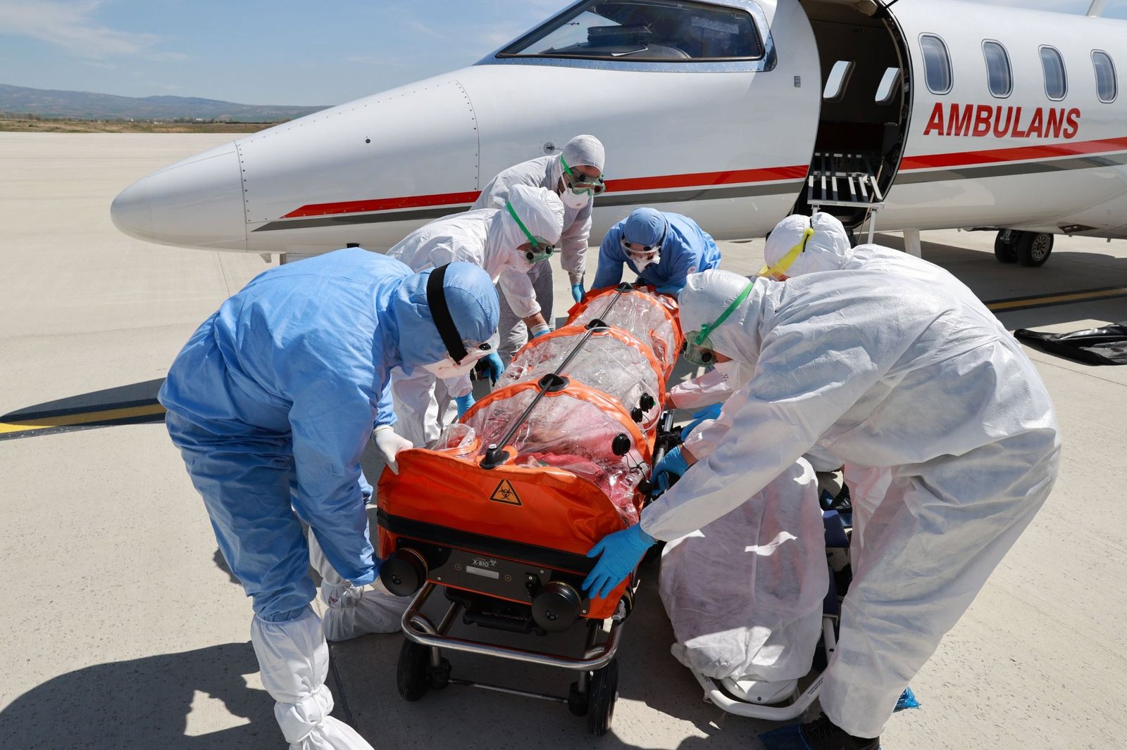 Medical team in protective suits loading an isolation stretcher onto an air ambulance jet — Illness on a Cruise: Evacuation and Repatriation
