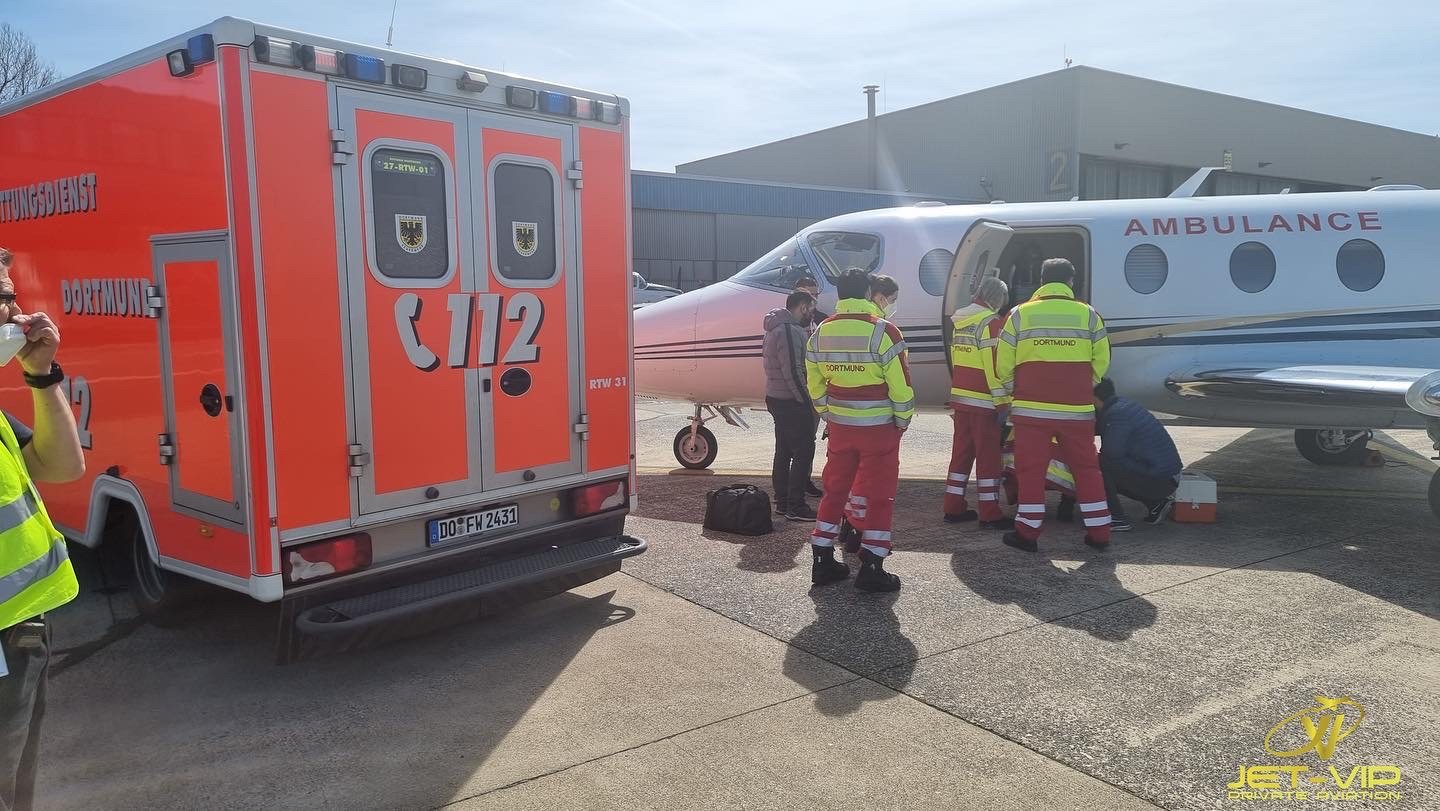 Medical crew loading a stretcher patient onto an Ambulance Flight air ambulance jet on the tarmac