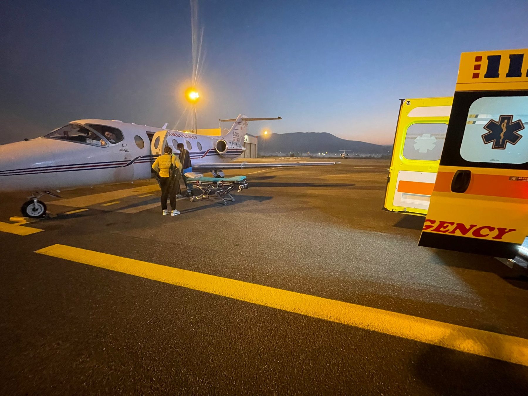 Avion-ambulance et ambulance terrestre sur le tarmac de nuit lors d'une mission d'évacuation sanitaire