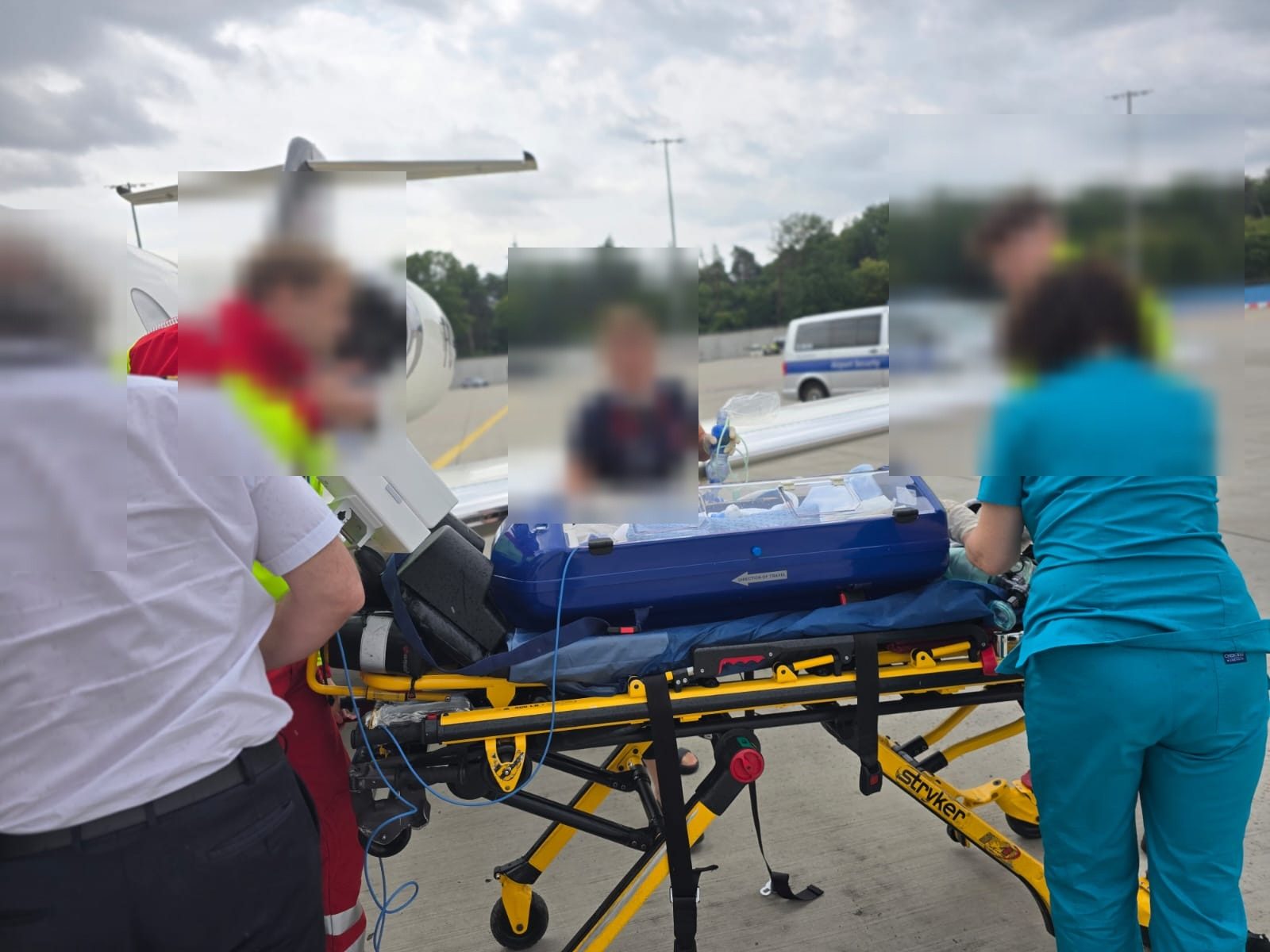Medical team caring for a young patient beside a neonatal transport incubator during an air ambulance mission